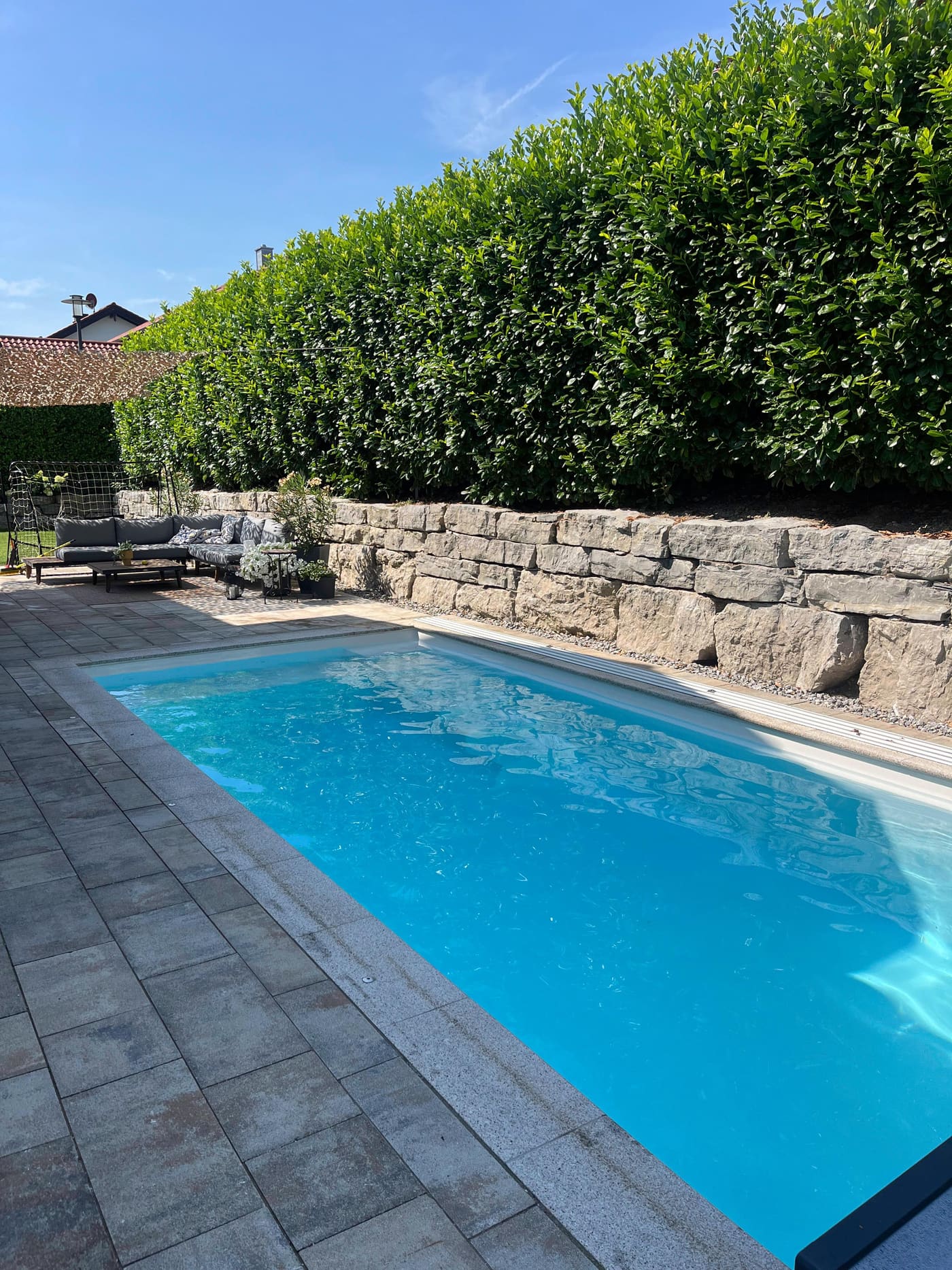 Fertig ausgeführter Pool mit Natursteinmauer und Gartenanlage